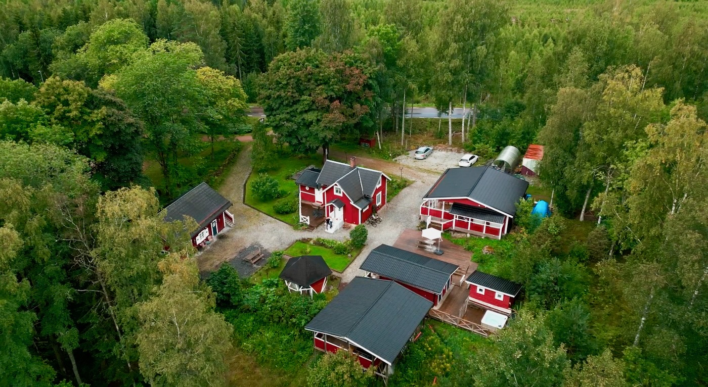 Aerial view of Mycelium Hub at Asphyttan, Sweden — red cabins among Värmland forest.